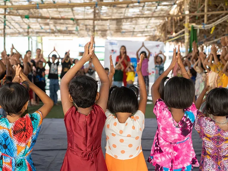 Children standing in a circle and clapping in a child-friendly space set up by Plan International
