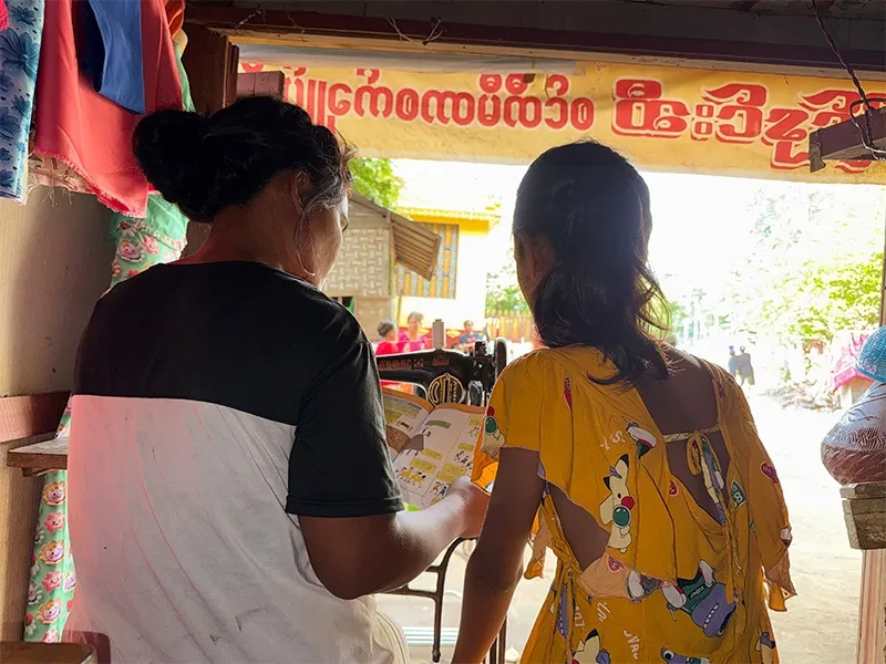 Backs of two people reading a booklet