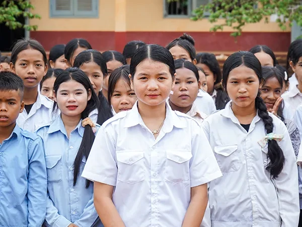 Phgnon, 16, from Cambodia, stands in front of her classmates. She has her hands clasped in front of her.