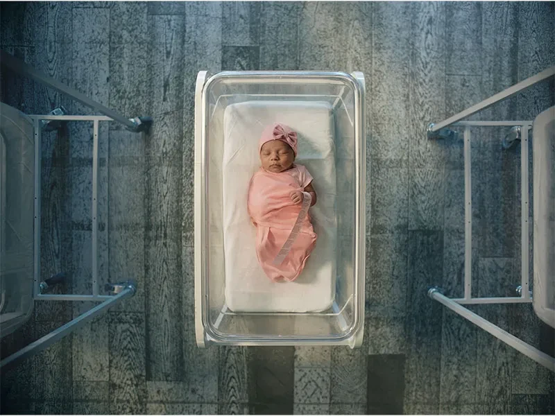 Arial shot of AI generated realistic looking baby wrapped in pink blanket and wearing pink hat in a crib