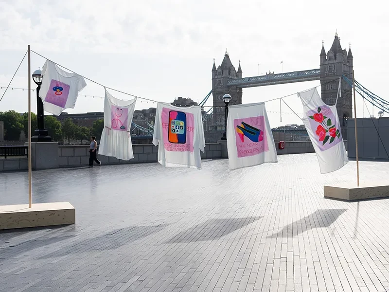A washing line of clothes is suspended in front of Tower Bridge.