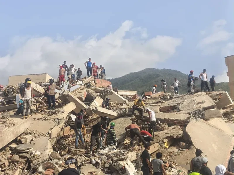 Dozens of people, including residents and uniformed personnel, search through the rubble of a collapsed building in Venezuela, following the 24 June 2026 earthquake.