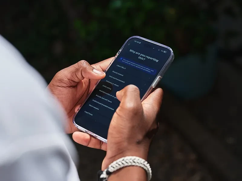 A young person uses a mobile phone to report harmful online content.