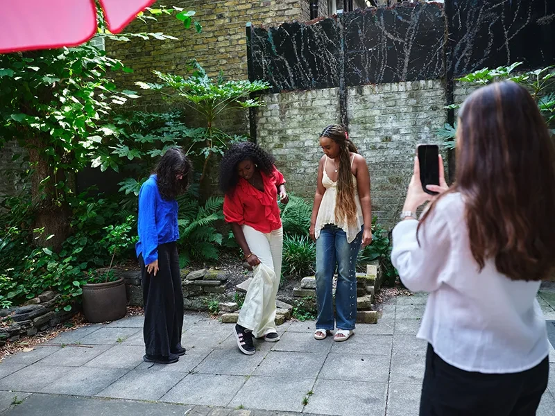 Three young people recreate social media trends using a phone to record.
