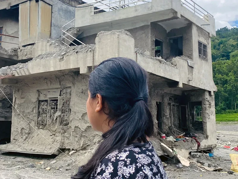 Back of Aditi's head looking out at collapsed buildings caused by floods in Nepal