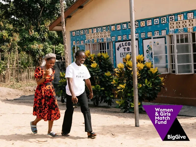 Two women walk by a house. There is a logo for the Big Give in the corner.