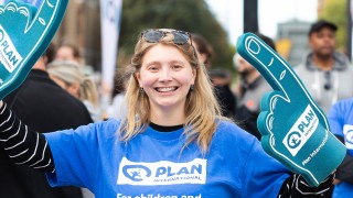Person in Plan UK t-shirt cheering at event