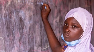 Zalissa, 14, writing on blackboard at school refurbished by Plan International 